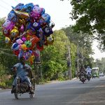 A differently-abled individual carries colorful balloon toys along Club Road in a bid to earn a livelihood