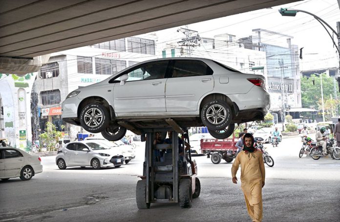 Traffic police official removing wrongly parked vehicle on Murree Road with the help of lifter