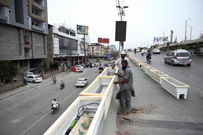 RDA workers install plant pots along a roadside bridge as part of a beautification and greening drive in the twin cities