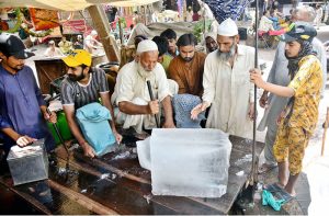 An elderly man transports an ice block on his bicycle for delivery at Khayyam Chowk to meet summer demand
