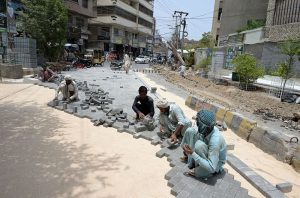 Labourers engaged in groundwork for the installation of cement tiles as part of road construction near Press Club Road.