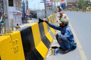 PHA staffers are busy paint the boundary wall of bridge during beautification work in the city.