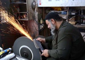 A man sharpens knives in preparation for the slaughter of sacrificial animals ahead of Eid ul Azha.