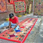 A worker crafts beautiful designs on a curtain chick and mats while selling on the footpath at Court Road