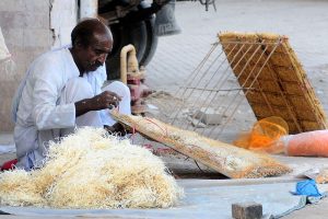 A vendor assembling different parts of room-coolers while sitting at roadside.