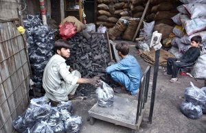 A vendor weighs charcoal for packing to meet the rising demand ahead of Eid ul Azha at a local market.