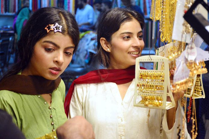 Girls busy in selecting and purchasing artificial jewelry from stall for preparation of upcoming Eid-ul-Azha in a local market