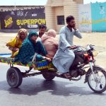 Gypsy family traveling on the tri-cycle rickshaw at Latifabad