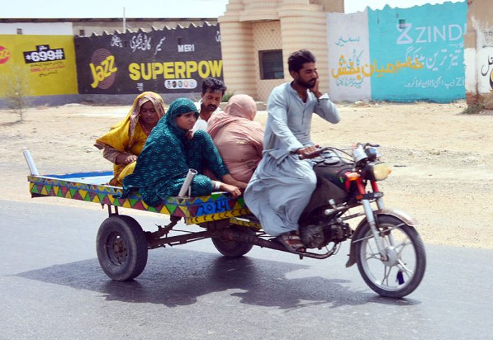 Gypsy family traveling on the tri-cycle rickshaw at Latifabad