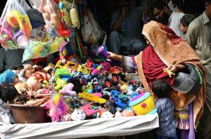 A woman is buying old toys for children from a shop. .