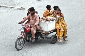 A nomad family travels on a motorcycle cart, relocating in search of relief from the ongoing heatwave as temperatures soar in the city