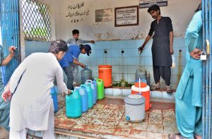 Residents queue up at a filtration plant with only two working taps amid the scorching heat in Pathan Colony