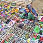A woman vendor displaying bangles to attract the customers in connection with upcoming Eidul Azha at Reshamgali