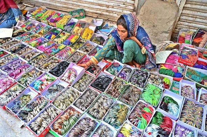 A woman vendor displaying bangles to attract the customers in connection with upcoming Eidul Azha at Reshamgali