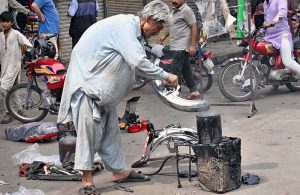 worker busy in his routine work outside motorcycle repairing shop at Mcleod road.