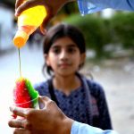 A young girl buys a tempting, colorful Ice Gola from a street vendor during the summer heat