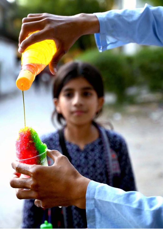 A young girl buys a tempting, colorful Ice Gola from a street vendor during the summer heat