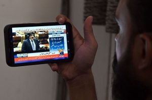 A citizen watches the live broadcast of the Sindh Budget 2025–26 on his mobile screen, presented by Sindh Chief Minister Syed Murad Ali Shah during the Sindh Assembly budget session