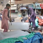 A labourer loads a block of ice onto a Suzuki pickup at a local ice factory to meet rising demand amid high temperatures