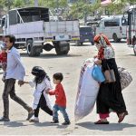 A couple and their children arrive at Pirwadai Bus Stand to depart for their hometown, where they will celebrate the upcoming Eid-ul-Azha with their family