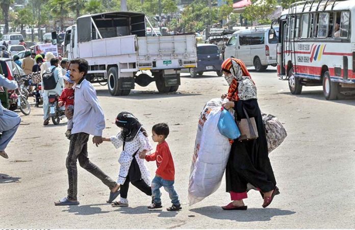 A couple and their children arrive at Pirwadai Bus Stand to depart for their hometown, where they will celebrate the upcoming Eid-ul-Azha with their family