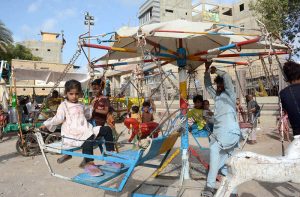 Children enjoy swing ride on the third day of Eid ul Azha at Chanesar Goth