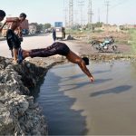 Youngsters dive into a pond to cool off and escape the scorching heatwave affecting the city