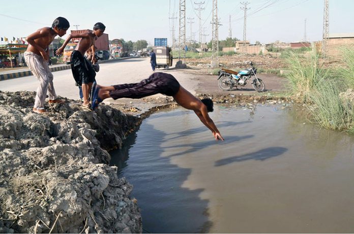 Youngsters dive into a pond to cool off and escape the scorching heatwave affecting the city