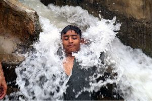 Youngsters dive into a pond to cool off and escape the scorching heatwave affecting the city