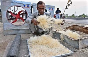 A worker prepares khas pads for room coolers at his workplace ahead of peak summer heat.