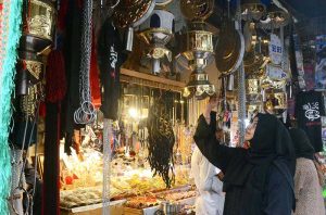 A woman selecting and purchasing items related to the Muharram procession.