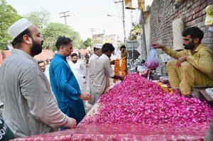 A woman recites verses from the Quran at the grave of her family member in a graveyard on the occasion of Eidul Azha