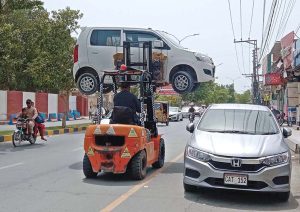 A traffic policeman uses a lifter to remove a wrongly parked vehicle blocking the traffic flow