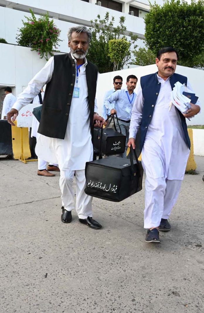 Pakistan’s Federal Board of Revenue (FBR) officials shift boxes with copies of the 2025–26 fiscal budget outside the Parliament House, before the start of the budget session