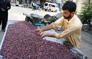 The vendor is decorating the summer fruit Falsa to attract customers at his roadside setup