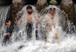 A young man enjoys a refreshing bath in a high-pressure stream to beat the scorching heat at Inqilab Road, Musazai area