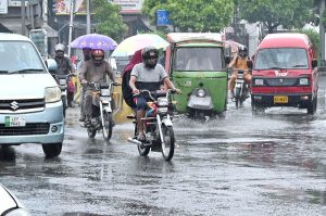 A woman holds an umbrella to shield herself from the rain while riding a motorcycle as the monsoon spell begins in the provincial capital.