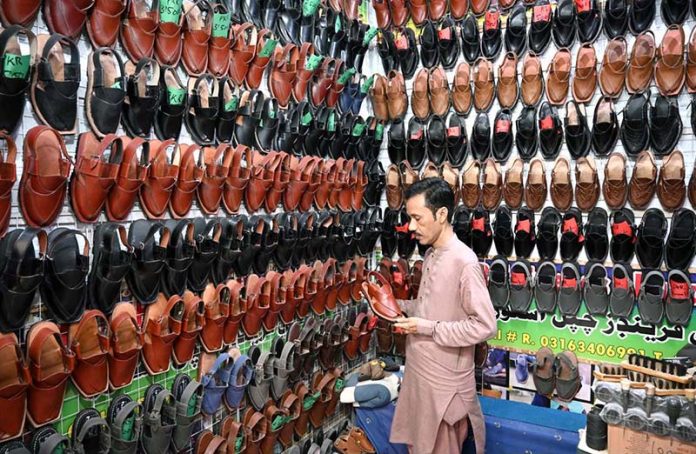 A person selecting traditional shoes from shop at Reshamgali for preparation of upcoming Eidul Adha