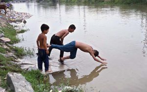 Youngsters enjoy jumping and bathing in a canal during hot weather in the city
