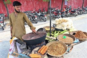A vendor preparing roasted corn to attract costumers.