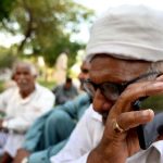 An elder man listening the 2025-26 federal budget live on his mobile phone at a roadside in the Federal Capital