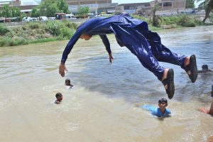Youngsters enjoy jumping and bathing in a canal during hot weather in the city