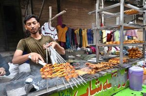 A vendor prepares BBQ at a roadside stall, drawing passersby with the tempting aroma of grilled meat.
