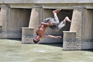 A young boy leaps into a canal to seek relief from the blistering summer heat gripping the city.