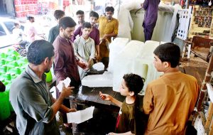 People purchase ice from a vendor at Bacha Khan Chowk to beat the summer heat.