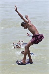 A young boy leaps into a canal to seek relief from the blistering summer heat gripping the city.