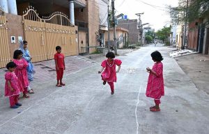 Children joyfully play the traditional street game Steppoo in front of their house during summer vacation.