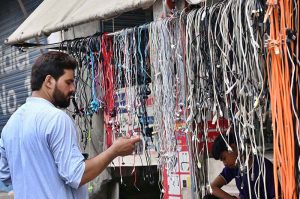 A vendor selling mobile phone charging wires at his roadside setup.