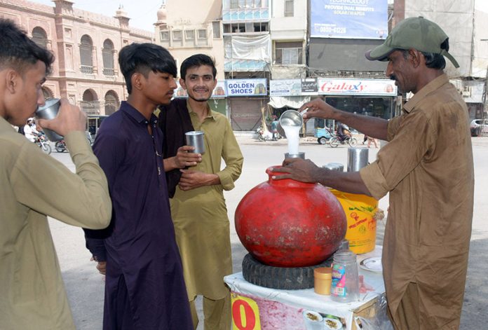 A vendor selling a traditional summer drink (Lassi) during the hot weather in the city