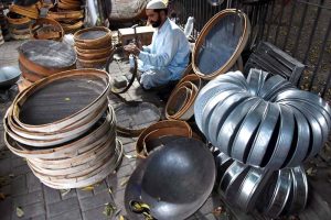 A man busy making a large wooden and stainless steel strainer (chanana) outside Delhi Gate in the provincial capital